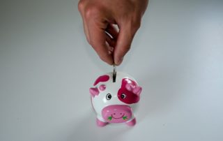 hand depositing coin in a piggybank