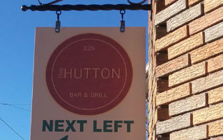 Sign for the Hutton bar and grill that says "next left"