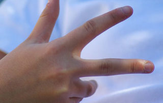 Photo of a child's hand with 3 fingers raised